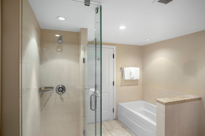 Modern bathroom with glass shower, soaking tub, and soft lighting.