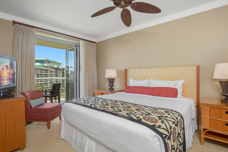 Spacious resort bedroom with balcony, tropical decor, and natural light.