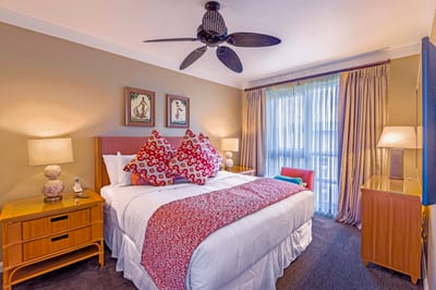 Charming tropical bedroom with vibrant pillows and natural sunlight glow.