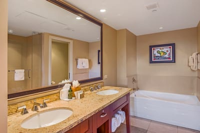 Spa-style bathroom with soaking tub, dual sinks, and artwork.