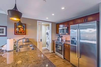 Gourmet kitchen meets island breeze—cook while enjoying views of the lanai, dining area, and tropical light