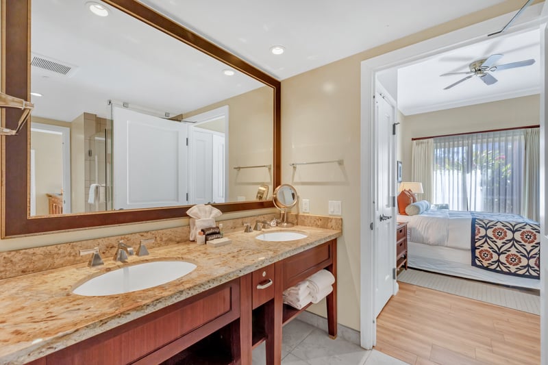 Spacious bathroom with granite double vanity and serene bedroom view.