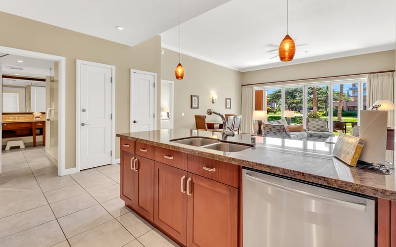 Island kitchen overlooks bright living room and lush tropical scenery.