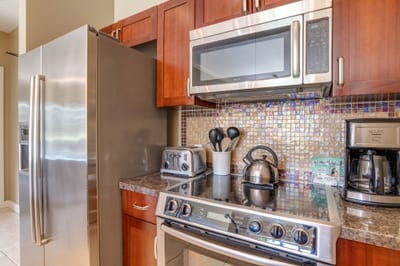 Stainless steel appliances and mosaic backsplash enhance cozy kitchen corner.