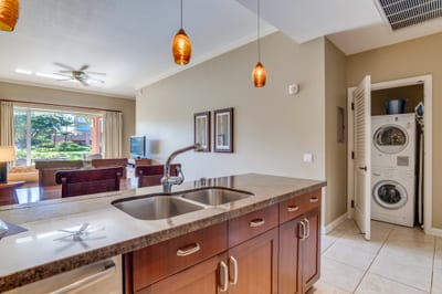 Warm pendant lighting accents modern kitchen with open layout and laundry.