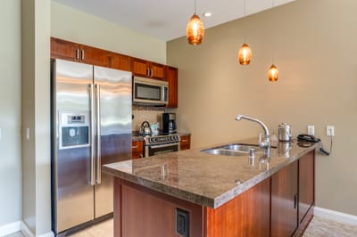 Sleek kitchen features granite island, pendant lighting, and stainless appliances.