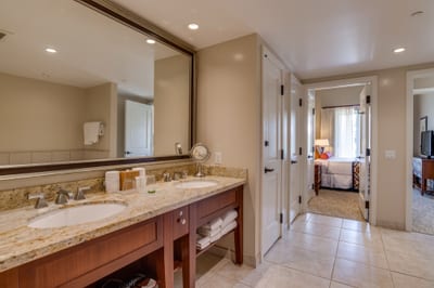 Elegant bathroom with granite counters and double sinks connects to bedroom.