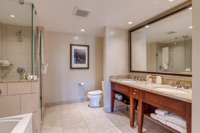 Spacious bathroom boasts granite counters, glass shower, and double sinks.