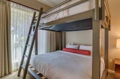 Bright bunk room with natural light, soft bedding, and cozy ambiance.