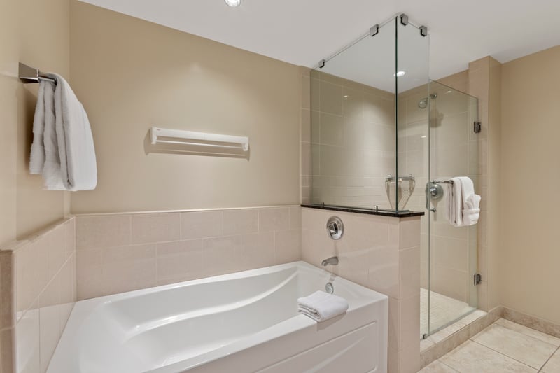 Elegant bathroom with soaking tub, glass shower, and fresh towels. HKK-112