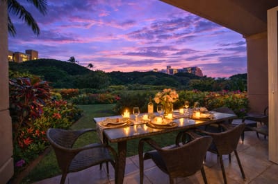Dine al fresco on your private lanai as sunset colors glow over lush resort grounds and a hint of ocean beyond.
