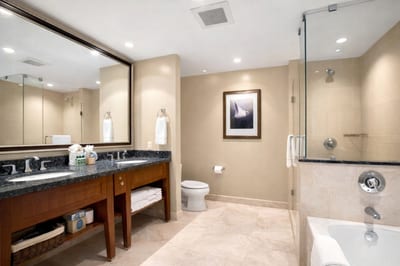 Refresh in your bathroom with a glass enclosed walk in shower and granite vanity, showcasing the complimentary L'Occitane bath amenities.