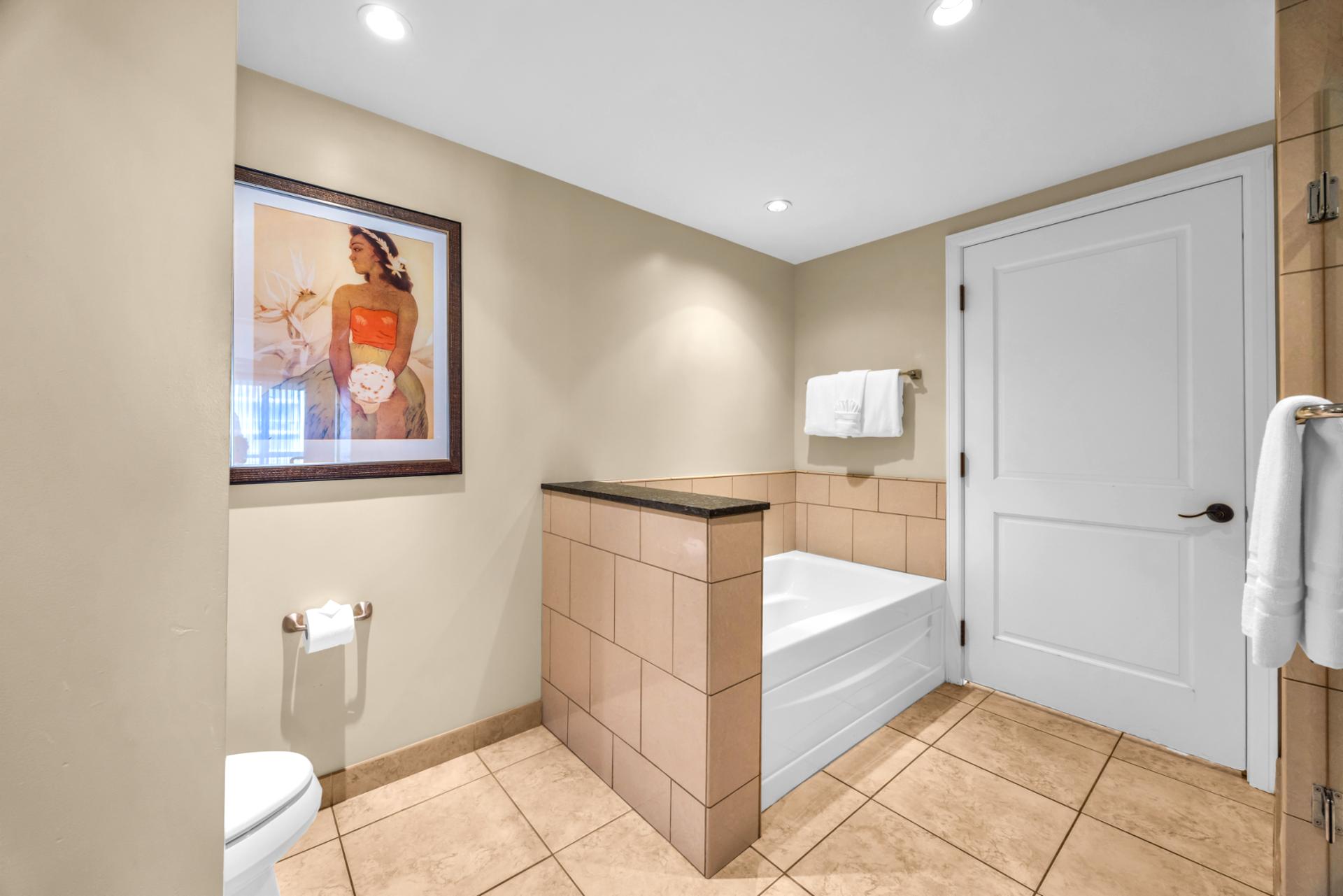 The guest bath features a separate glass shower and bath tub, perfect for unwinding after a day of exploring Maui