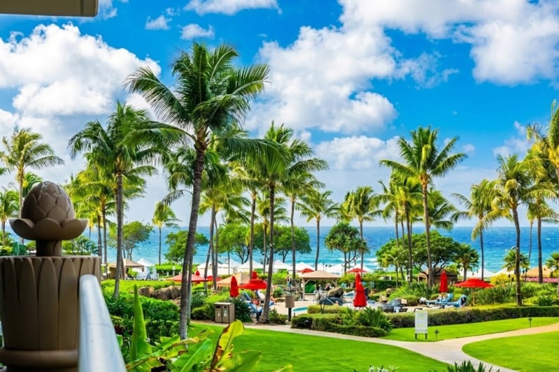 Stroll past lush lawns and palms with the ocean on the horizon, an easy preview of the Honua Kai beachfront setting.