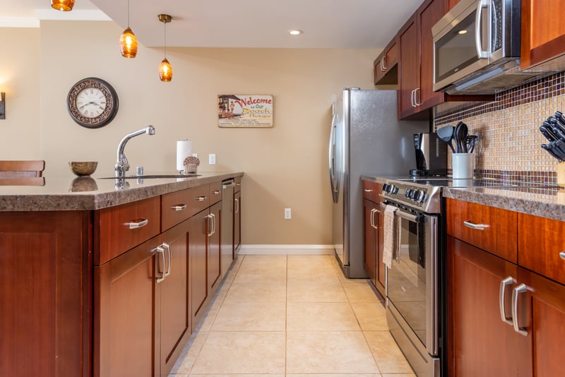 Modern island kitchen with stainless appliances, mosaic backsplash, and warm lighting. HKK-225