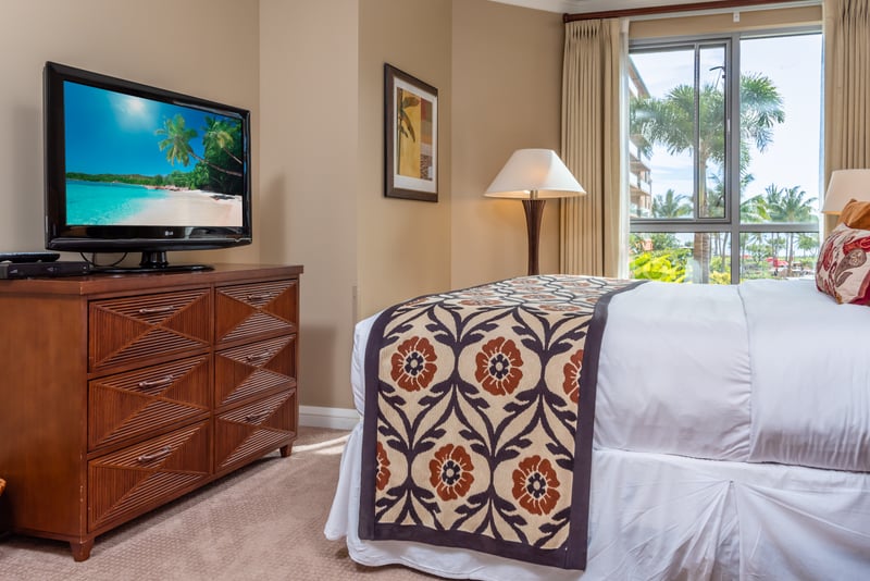 Bright bedroom with beach view, cozy bed, TV, and dresser. HKK-225