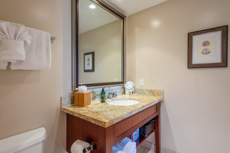 Chic single-sink vanity with granite counter, large mirror, and storage.