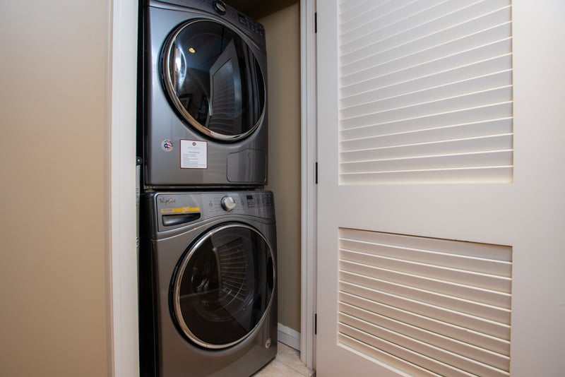 Modern stacked washer and dryer tucked neatly behind louvered closet doors. HKK-225
