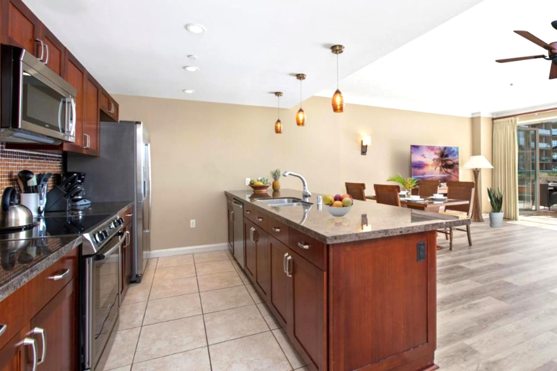 Open-concept kitchen flows into tropical dining and outdoor paradise views.