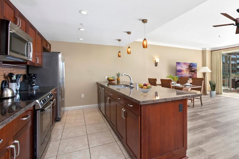 Open-concept kitchen flows into tropical dining and outdoor paradise views.