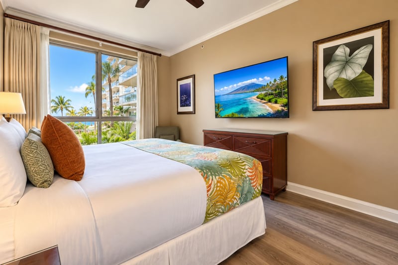 Ocean and palm views fill the guest bedroom window, with a wall-mounted TV, wide dresser, and ceiling fan for comfortable nights. HKK-229