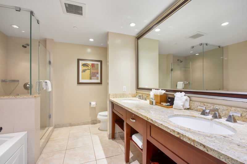 Elegant bathroom with granite counters, glass shower, and tropical decor.
