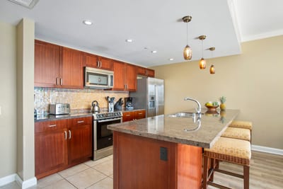 Sleek island kitchen with granite counters, pendant lights, and charm.
