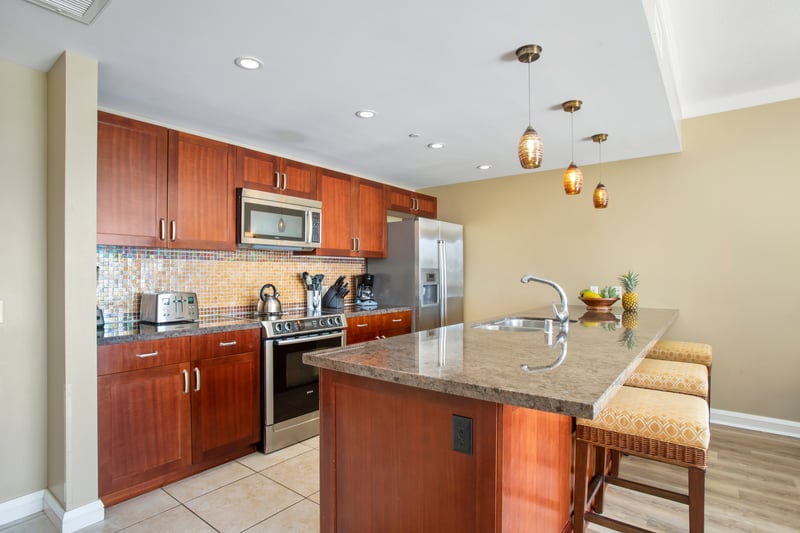Sleek island kitchen with granite counters, pendant lights, and charm.