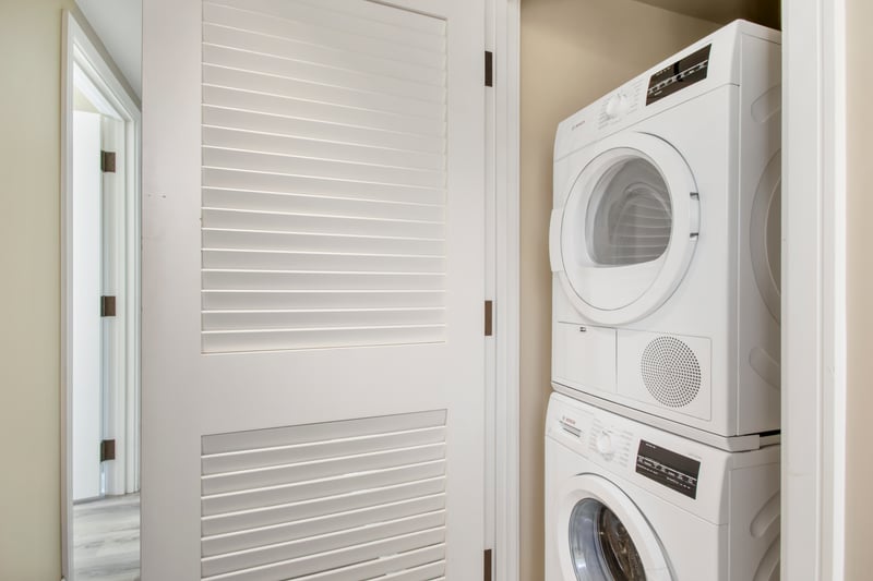 Compact laundry closet with stacked Bosch washer and dryer units.