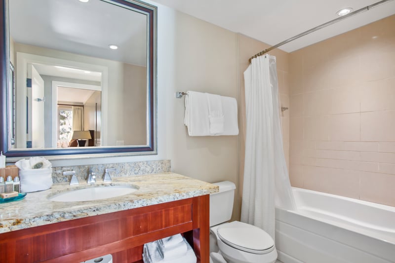 Modern bathroom with granite countertop, full tub, and fresh towels. HKK-229