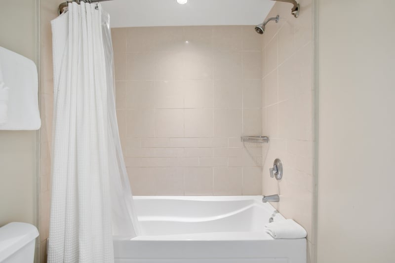 Spacious tiled bathtub with rainfall shower and soft white curtain. HKK-229