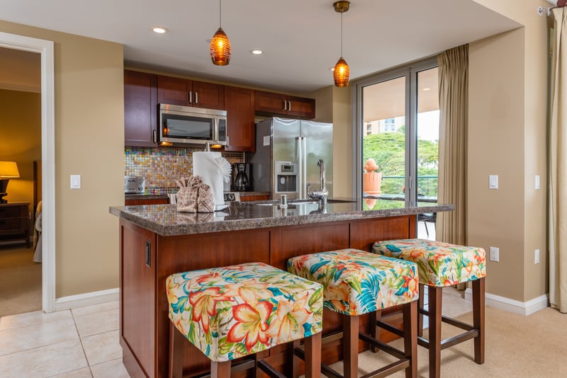 Vibrant kitchen island with tropical barstools and modern stainless appliances
