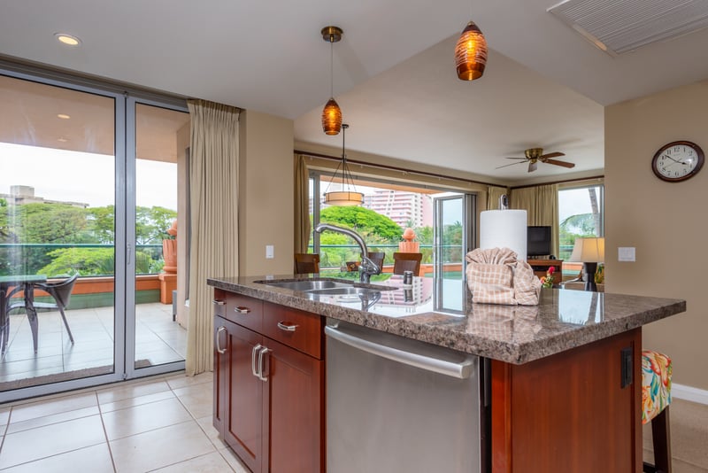 Granite kitchen island with pendant lighting and scenic lanai access