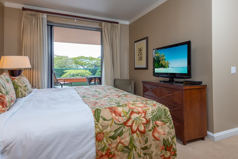 Bright bedroom sanctuary with floral linens and lanai access