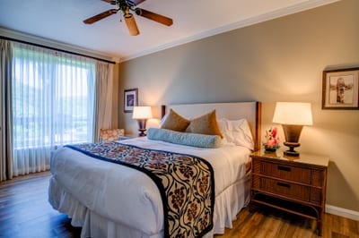 Sunlit bedroom with tropical accents and cozy, inviting king-size bed.