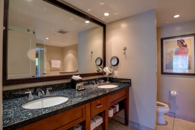 Granite double vanity with private toilet nook and island-inspired decor.