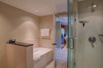 Modern bathroom with soaking tub, glass shower, and hallway view.