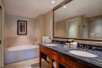 Relaxing soak tub beside elegant double sinks and granite bathroom vanity.