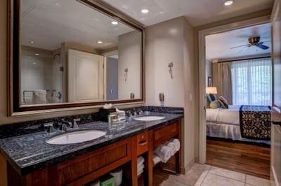 Elegant double vanity bathroom connects seamlessly to cozy tropical bedroom suite.