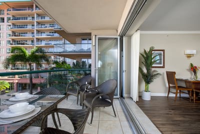 Elegant indoor-outdoor living with balcony dining and tropical resort views.