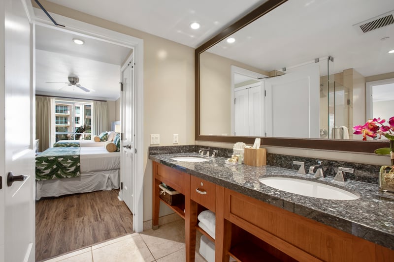 Elegant vanity area with double sinks and tropical bedroom view.