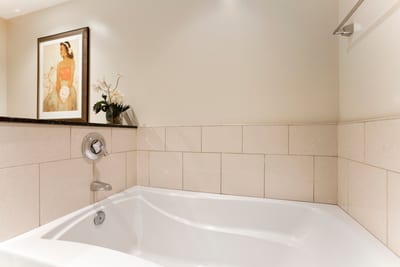 Serene soaking tub with floral accents and calming island-inspired art.