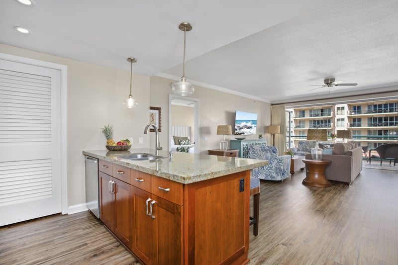 Modern kitchen island overlooking inviting coastal living space and scenic lanai.