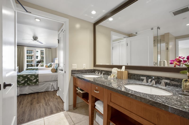 Spacious bathroom with granite vanity and view into tropical bedroom retreat.