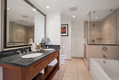 Luxurious bathroom with granite vanity, soaking tub, and glass shower