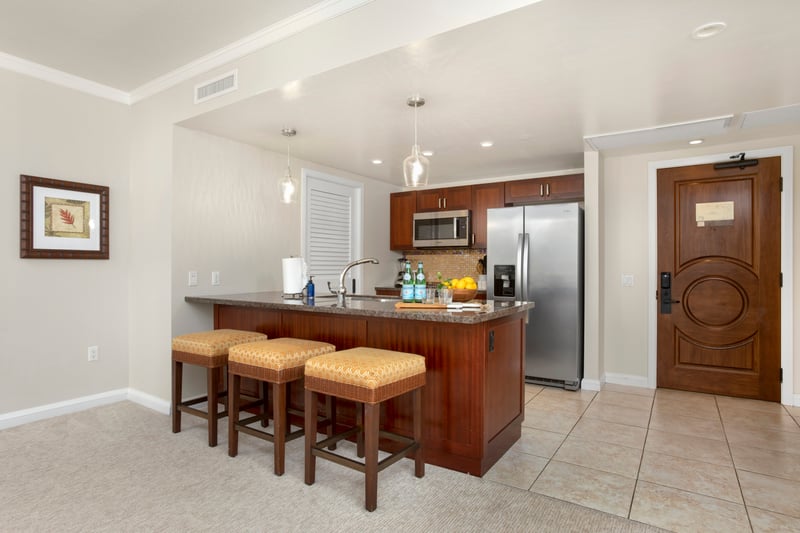 Modern island kitchen with breakfast bar, stainless appliances, and warm lighting.