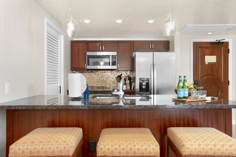 Stylish kitchen island with bar seating, stainless appliances, and mosaic backsplash.