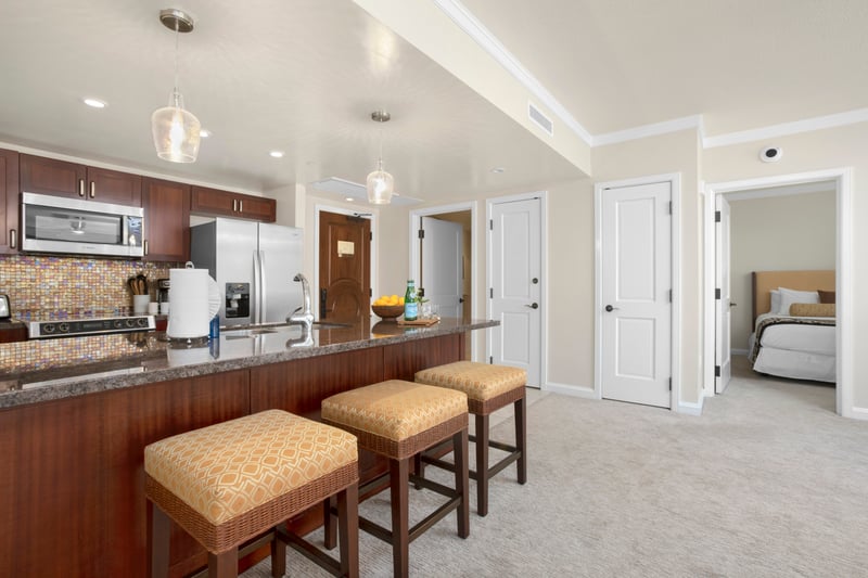 Inviting kitchen with bar seating, elegant lighting, and cozy bedroom view.