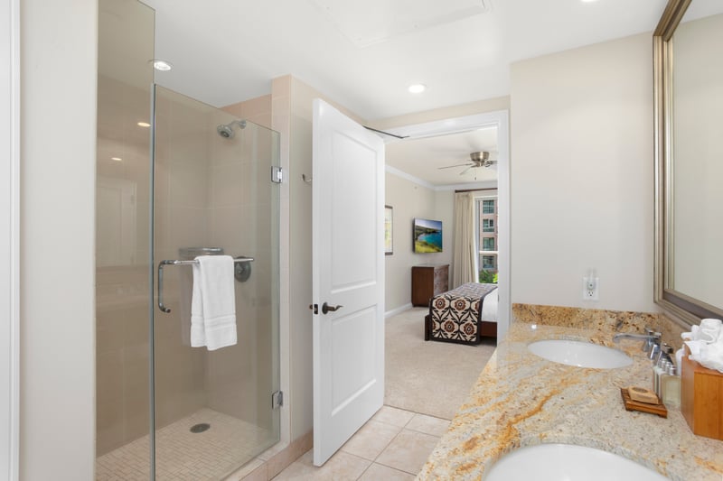 Elegant ensuite bath with glass shower, granite counters, and bedroom view.