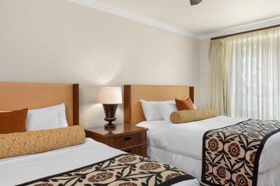 Bright guestroom with double beds, island accents, and natural light.